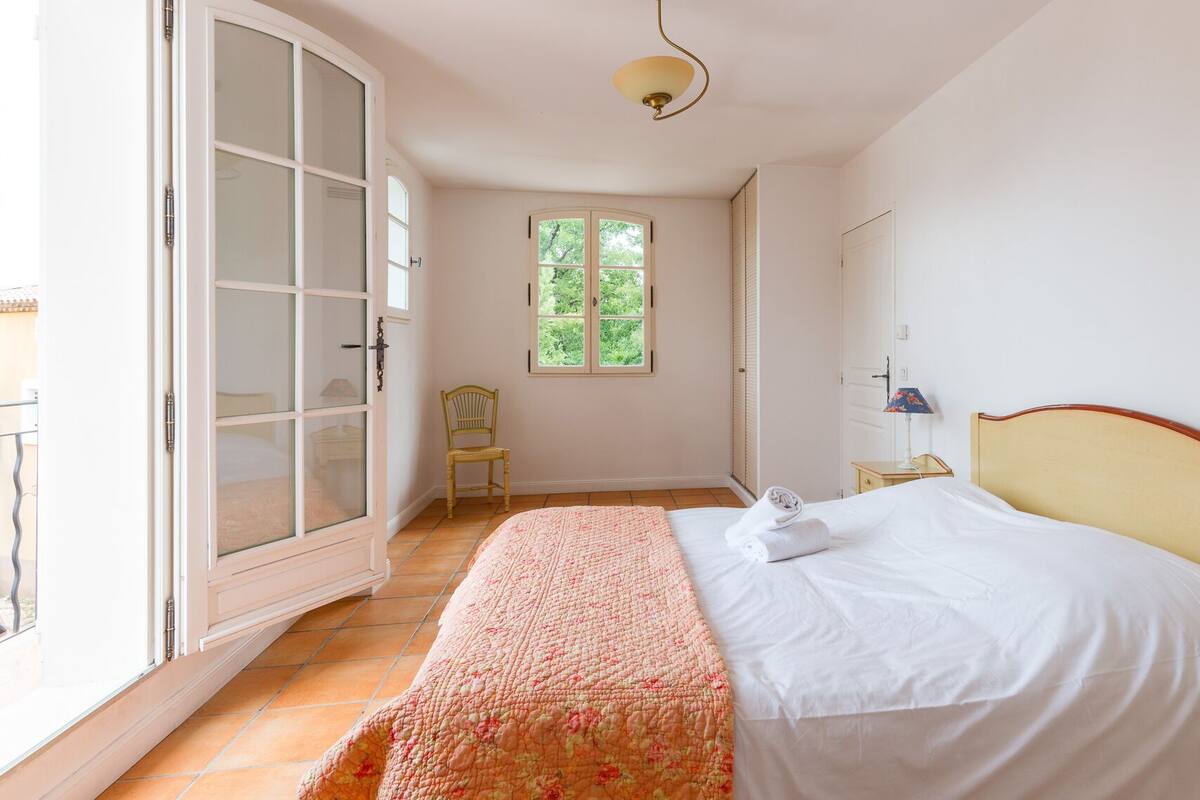 Ein Schlafzimmer mit Bett, Stuhl, Fenster und Kleiderschrank.