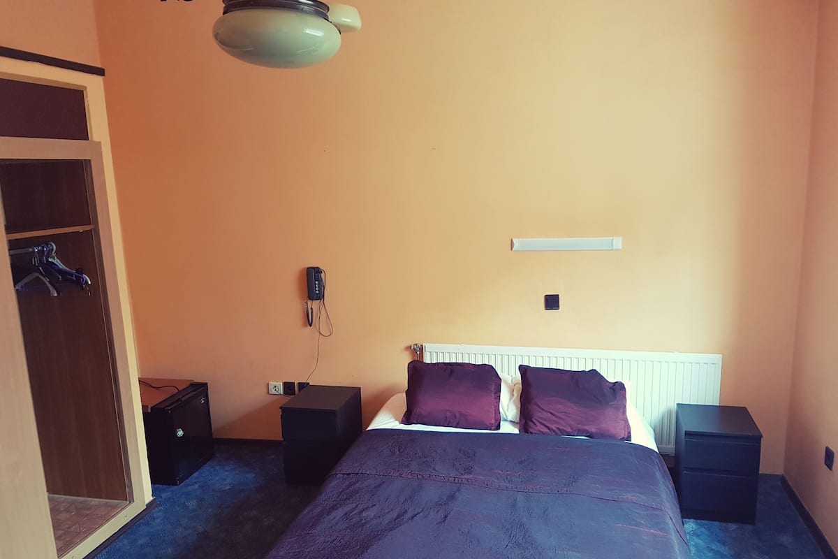 Ein Schlafzimmer mit einem Bett, einem Kleiderschrank, einem Heizgerät und einem Telefon.