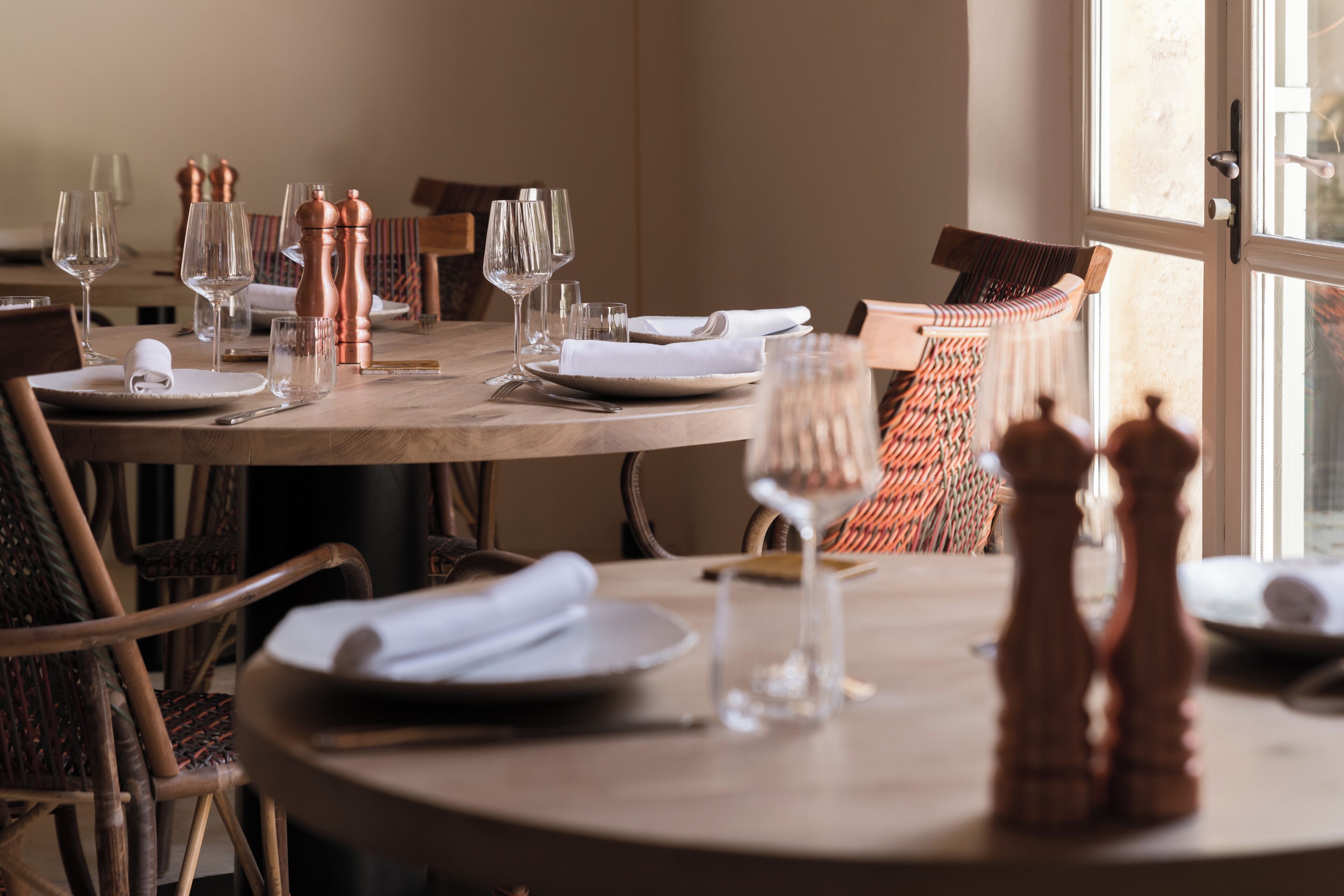 Une table à manger dressée avec des assiettes, des couverts et des verres à vin, ainsi que des salières et des poivrières posées sur la table.