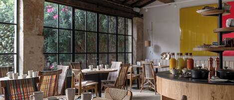 A restaurant interior with round tables, chairs, and a bar area with kitchen equipment.