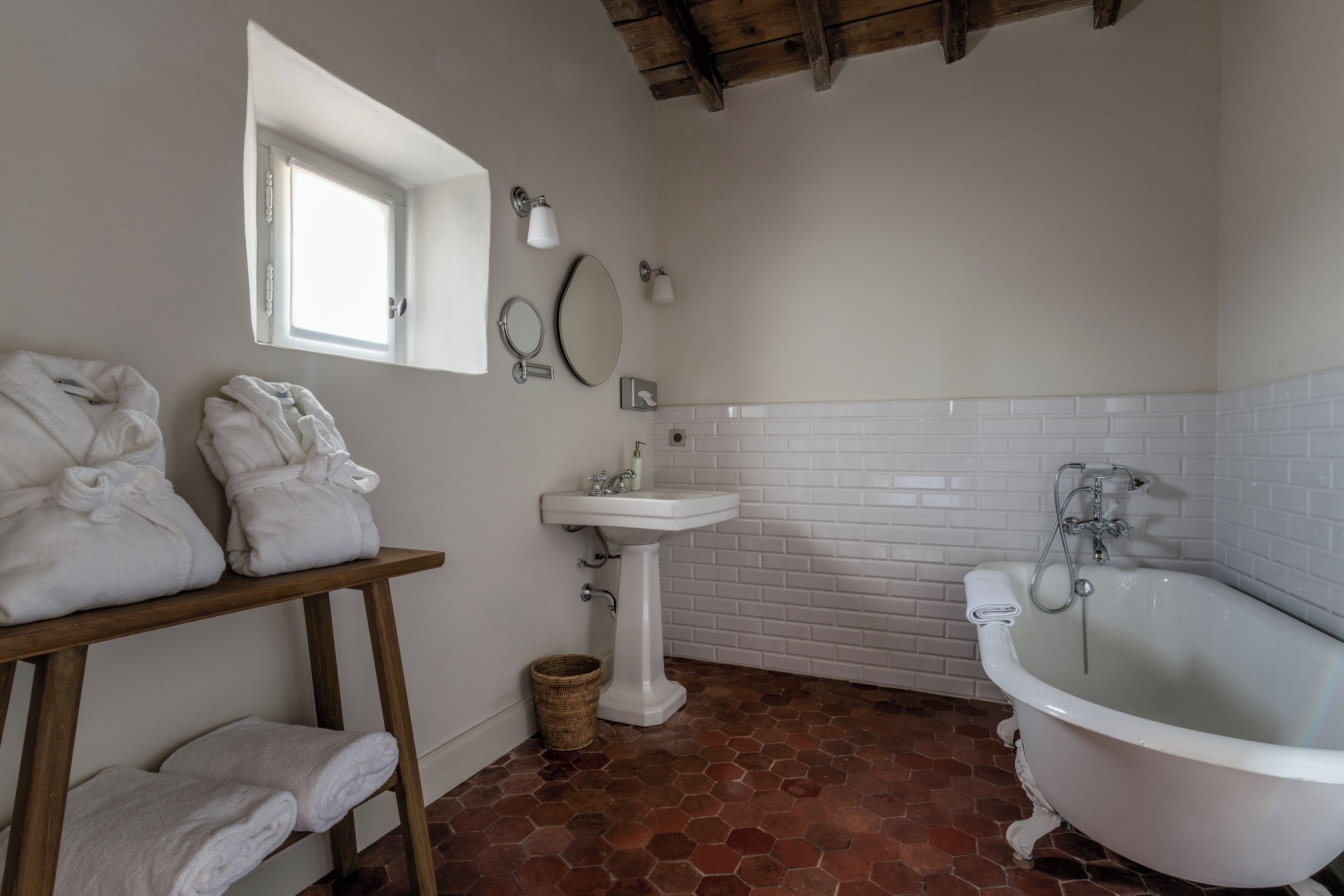 Ein Badezimmer mit einem weißen Waschbecken, einer freistehenden Badewanne und zwei weißen Handtüchern auf einem Holzboden.