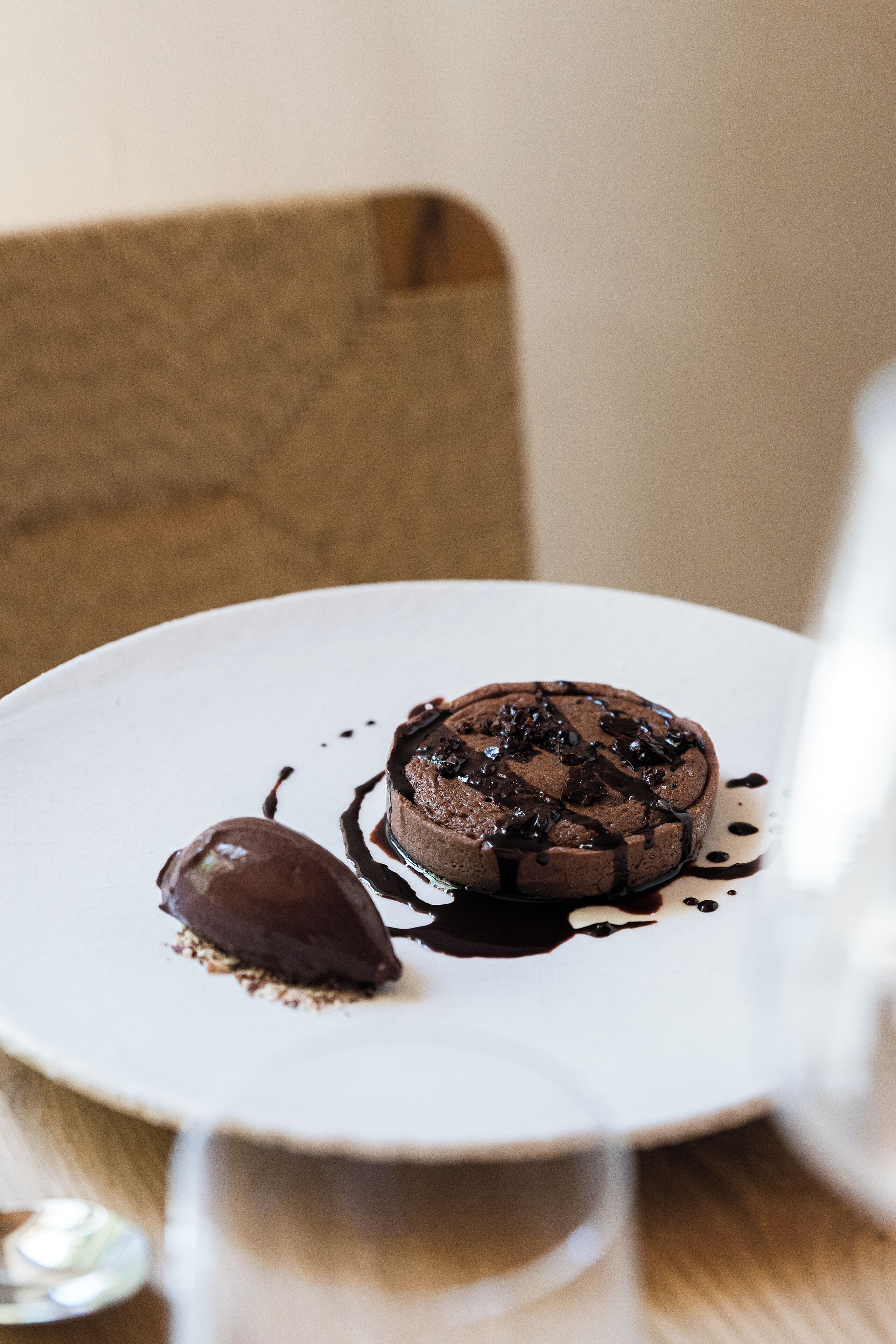 A dessert on a white plate with chocolate sauce and a scoop of ice cream.