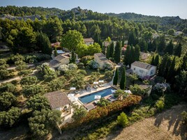 Vista aérea de una zona residencial con piscina, varias casas y abundante vegetación.