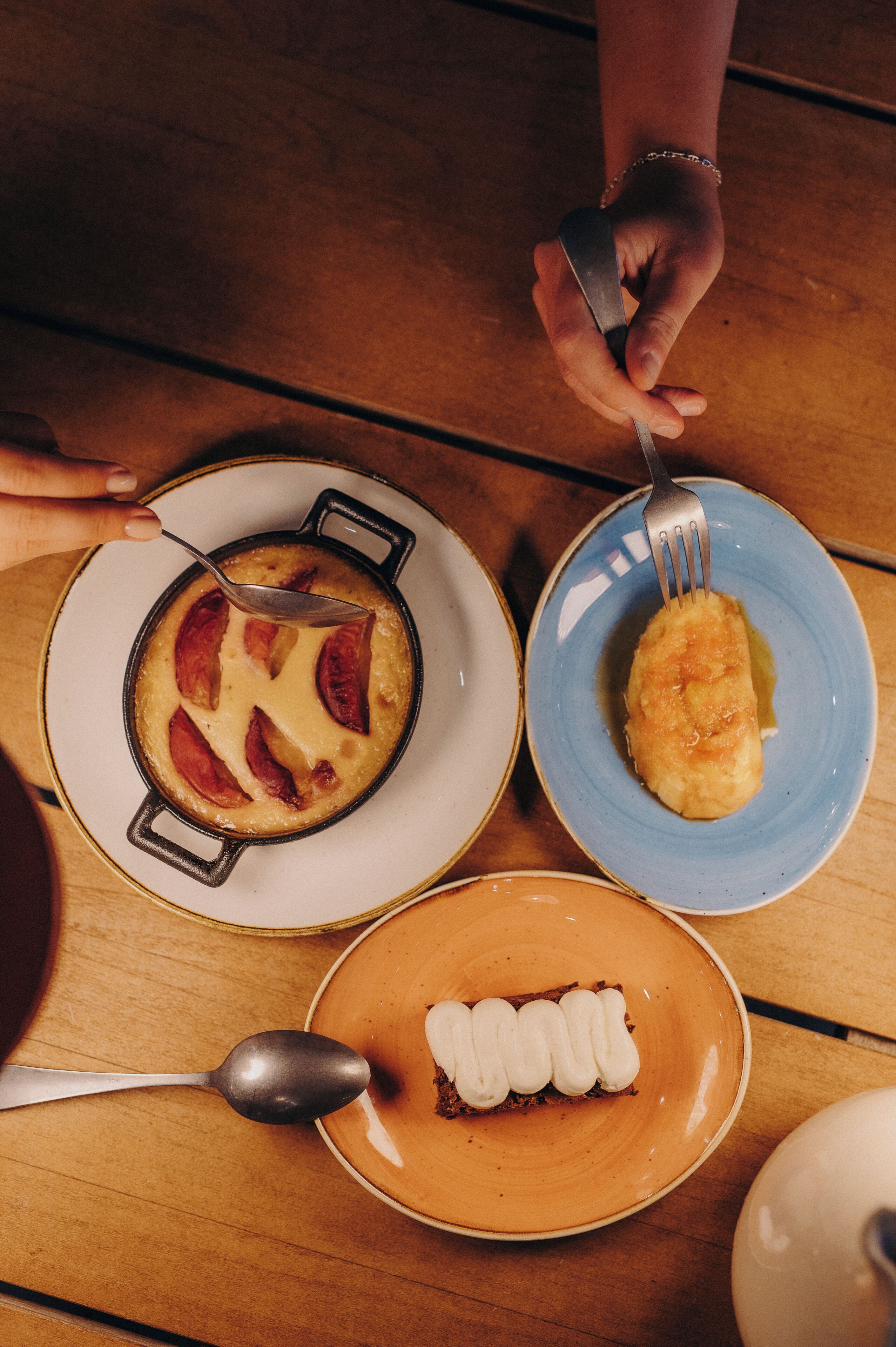 A dining table with three plates of food, a spoon, and a fork.