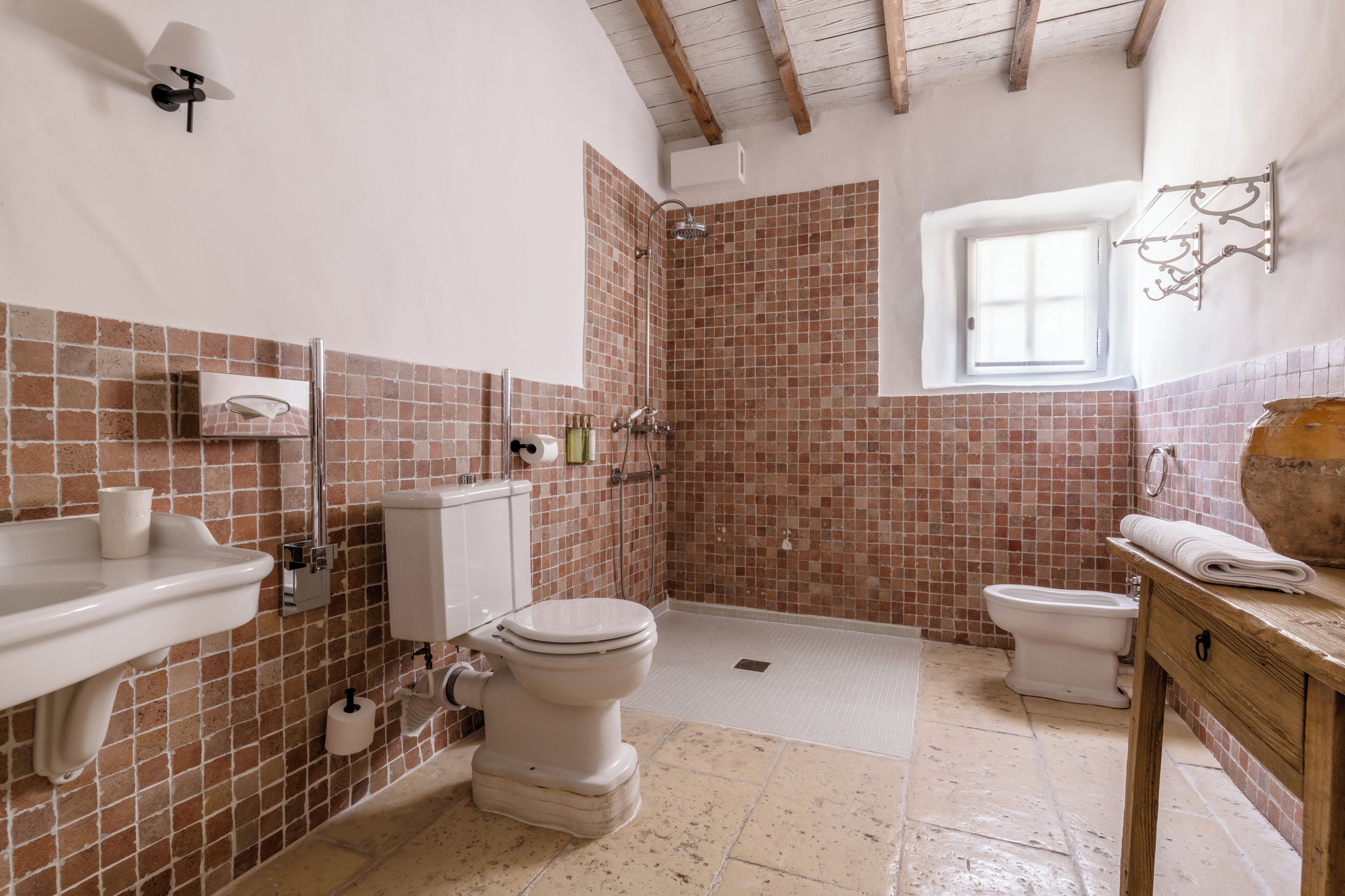 A bathroom with a shower, toilet, sink, and a window.