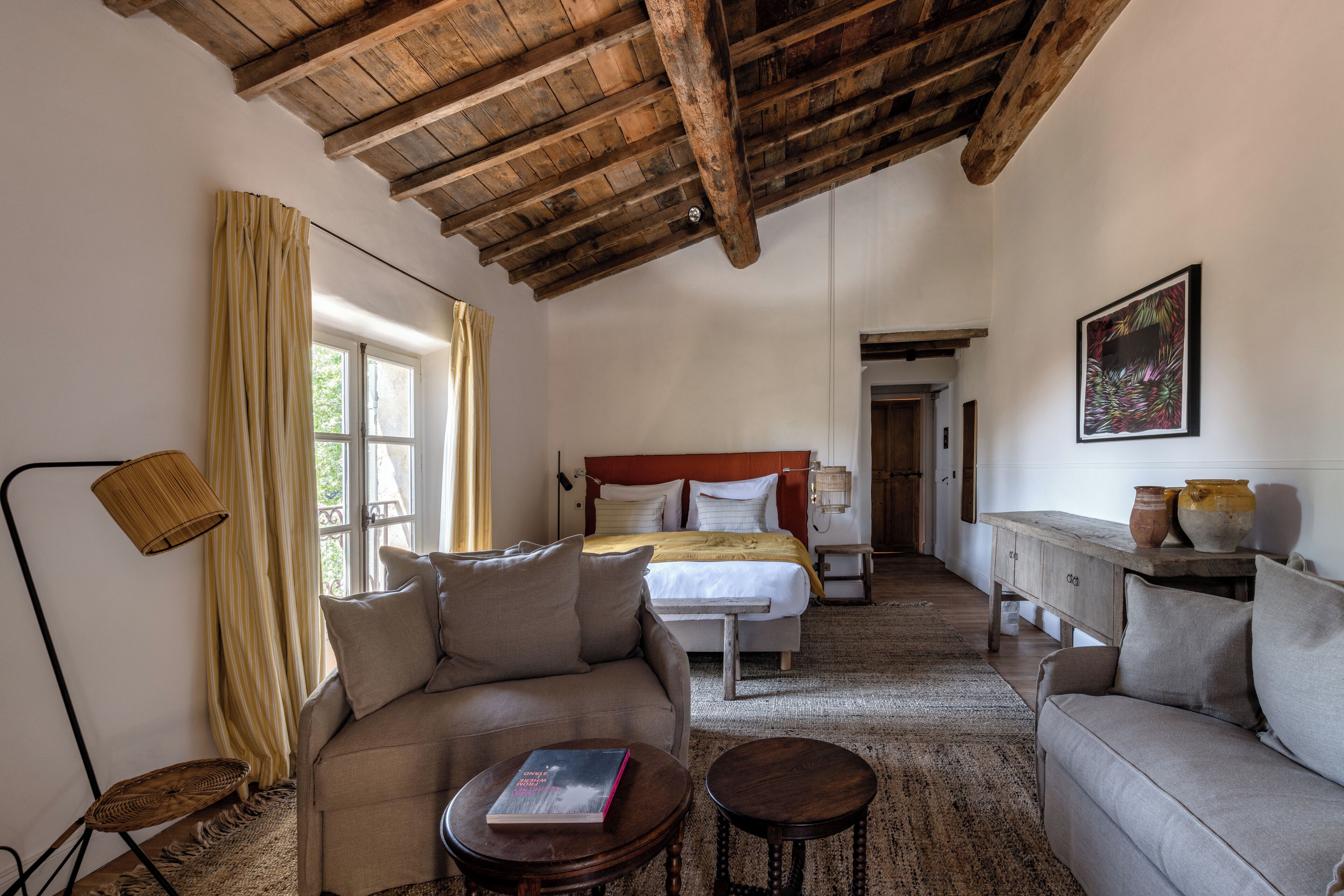 A cozy room with a bed, two sofas, a small table, and a lamp.