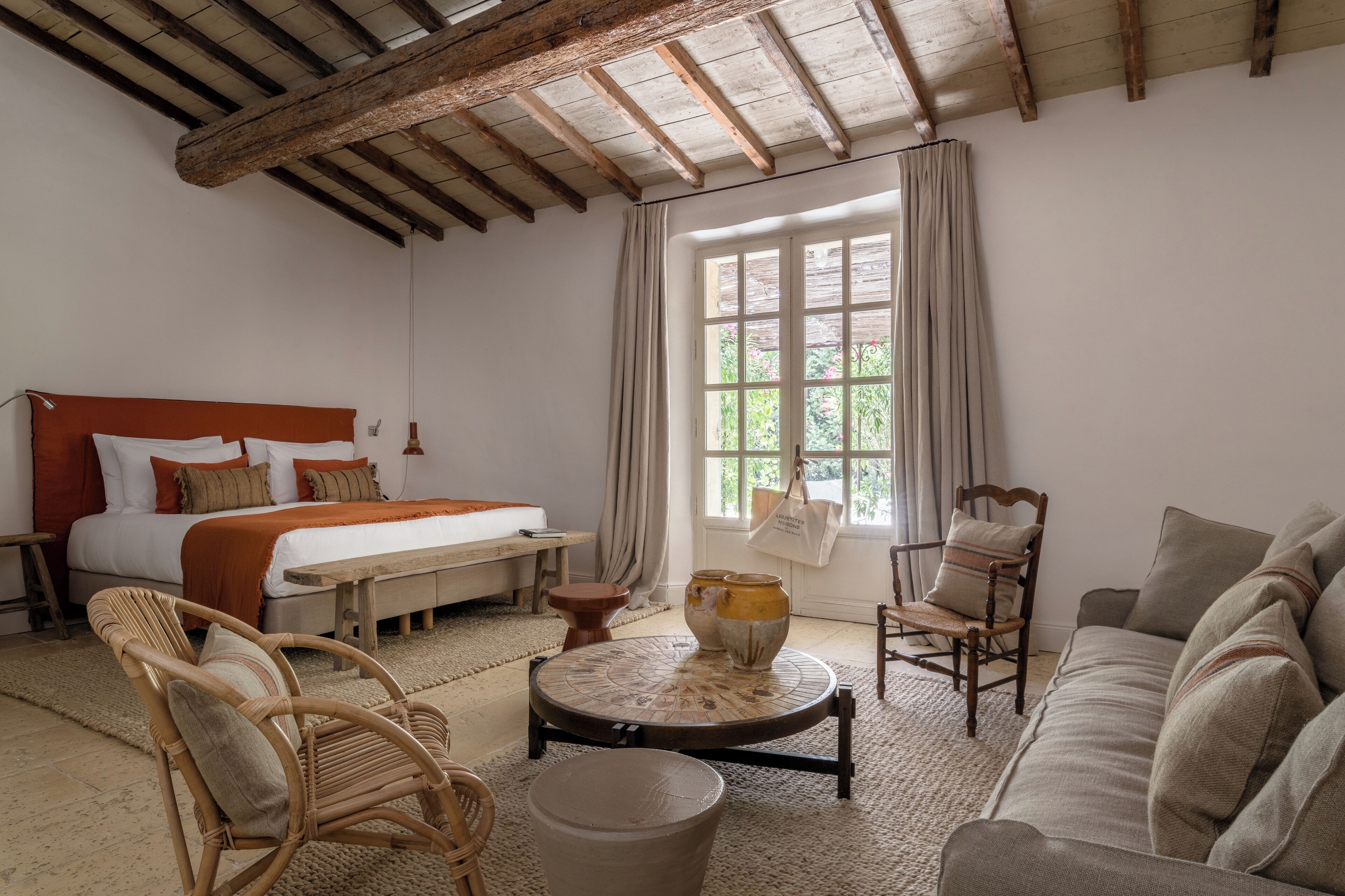 Una camera da letto con un letto, un divano, una sedia, un tavolo e una finestra con tende.