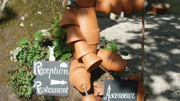 A sculpture of a person made from terracotta pots, with directional signs pointing to 'Reception' and 'Ascenseur'.
