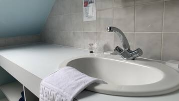 A modern bathroom with a white sink, a silver faucet, and a towel on the counter.