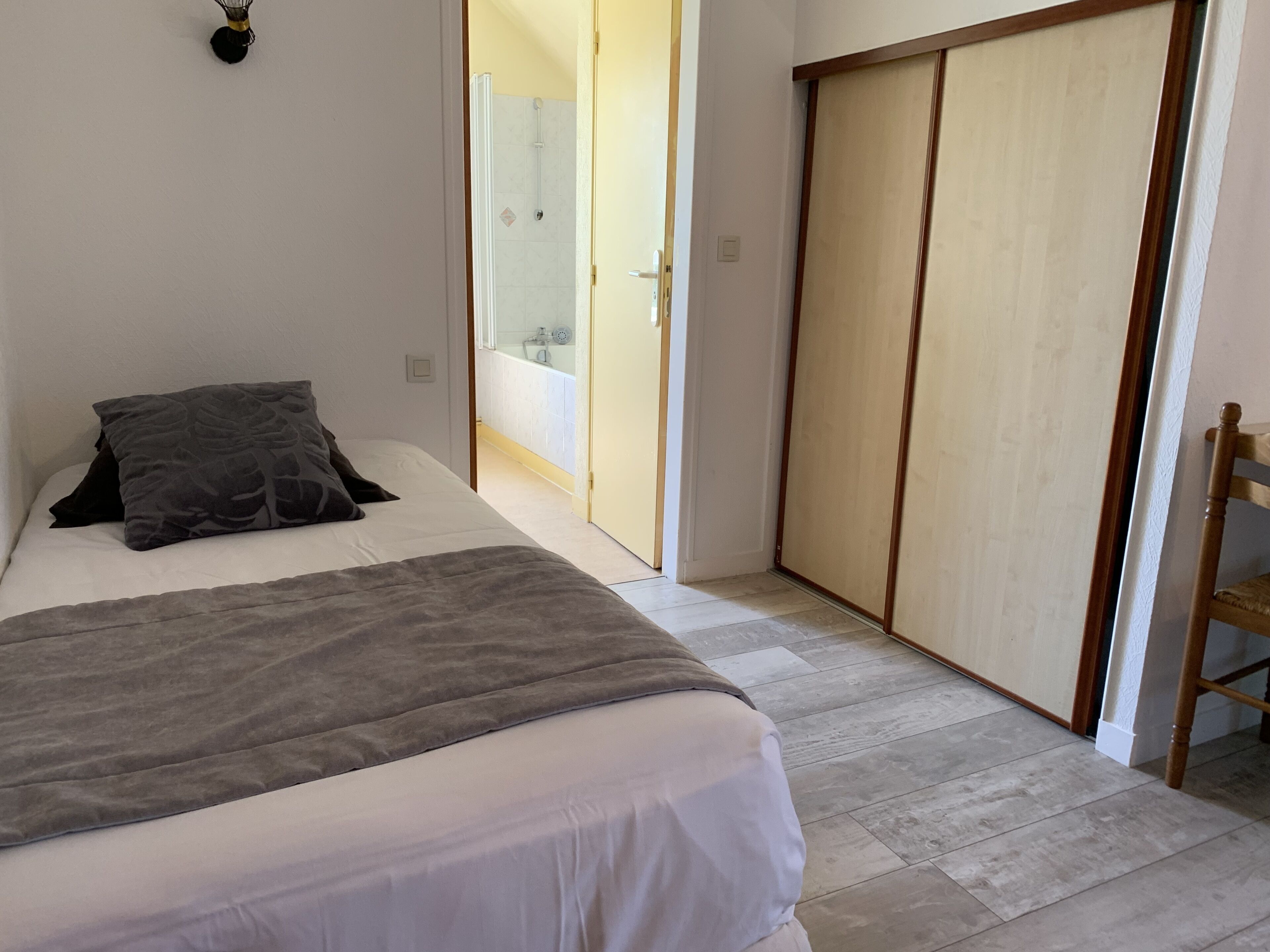 Una camera da letto con un letto, un comodino, un armadio e un bagno visibile attraverso una porta aperta.