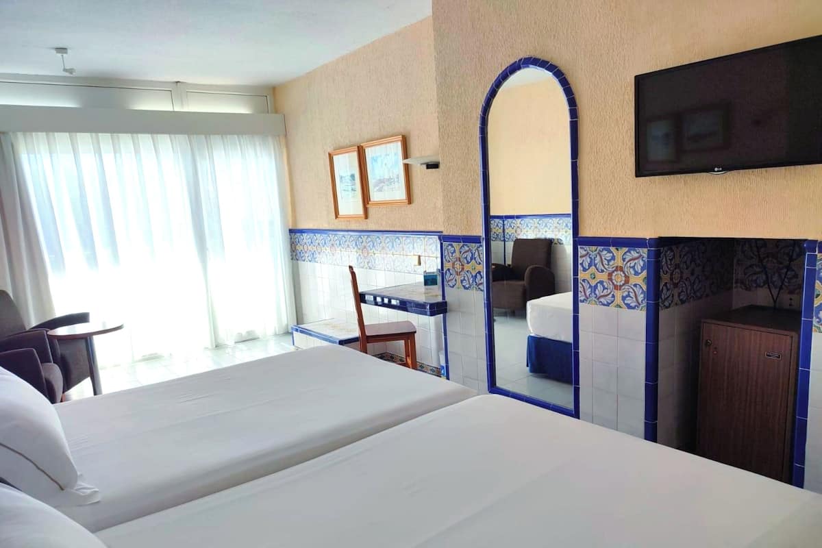 Une chambre d’hôtel avec un grand lit, un bureau, une chaise, une télévision et une armoire.