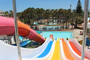 Ein Wasserpark mit mehreren Rutschen und einem Poolbereich, umgeben von Palmen.