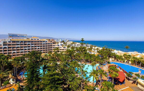 Ein Hotel mit mehreren Etagen, einem Poolbereich und Blick aufs Meer.