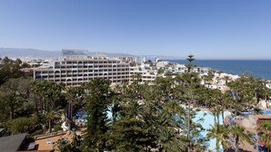 Un resort con varias piscinas, palmeras y vista al océano.