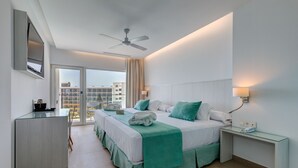 Habitación de hotel moderna con cama, escritorio, ventilador de techo y vistas a la ciudad.
