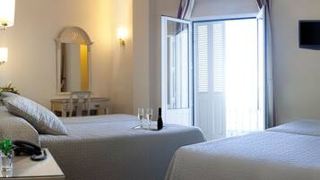 A hotel room with two beds, a desk with a phone and a glass of water, a chair, a table, a mirror, and a TV on the wall.