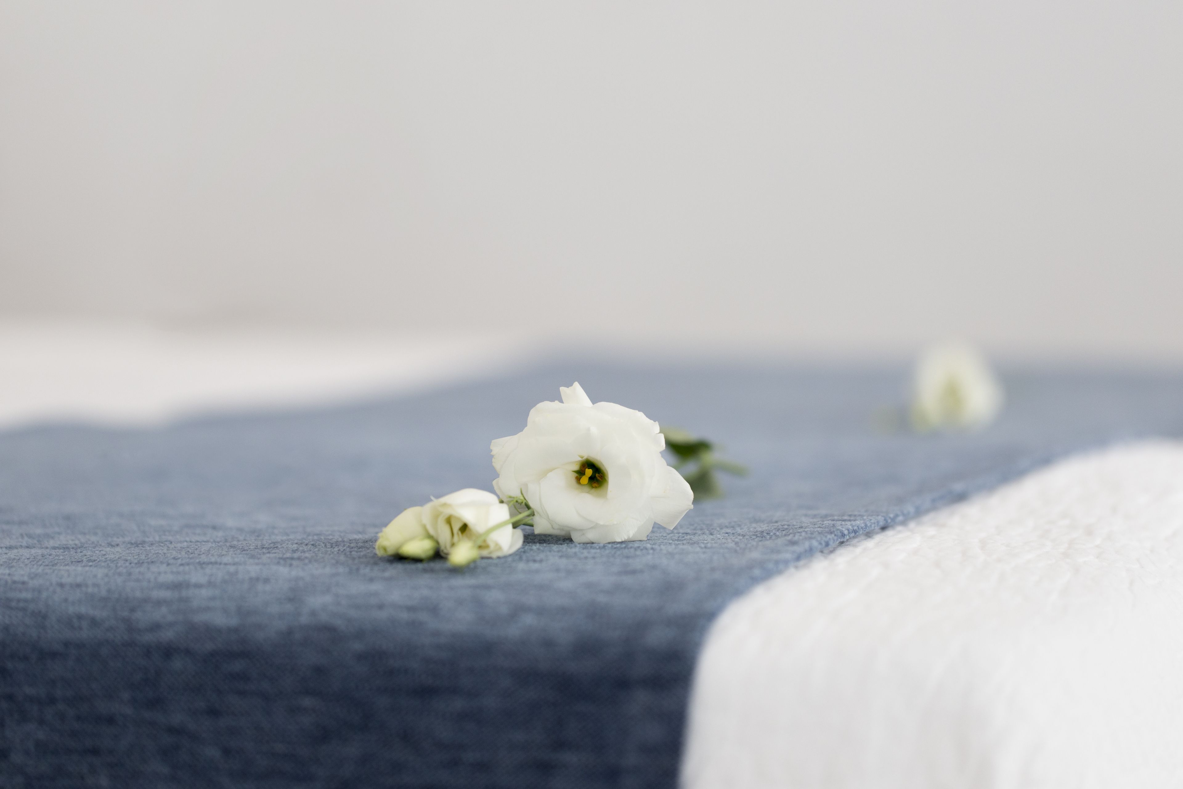 A bed with a blue bedspread and white bedding.