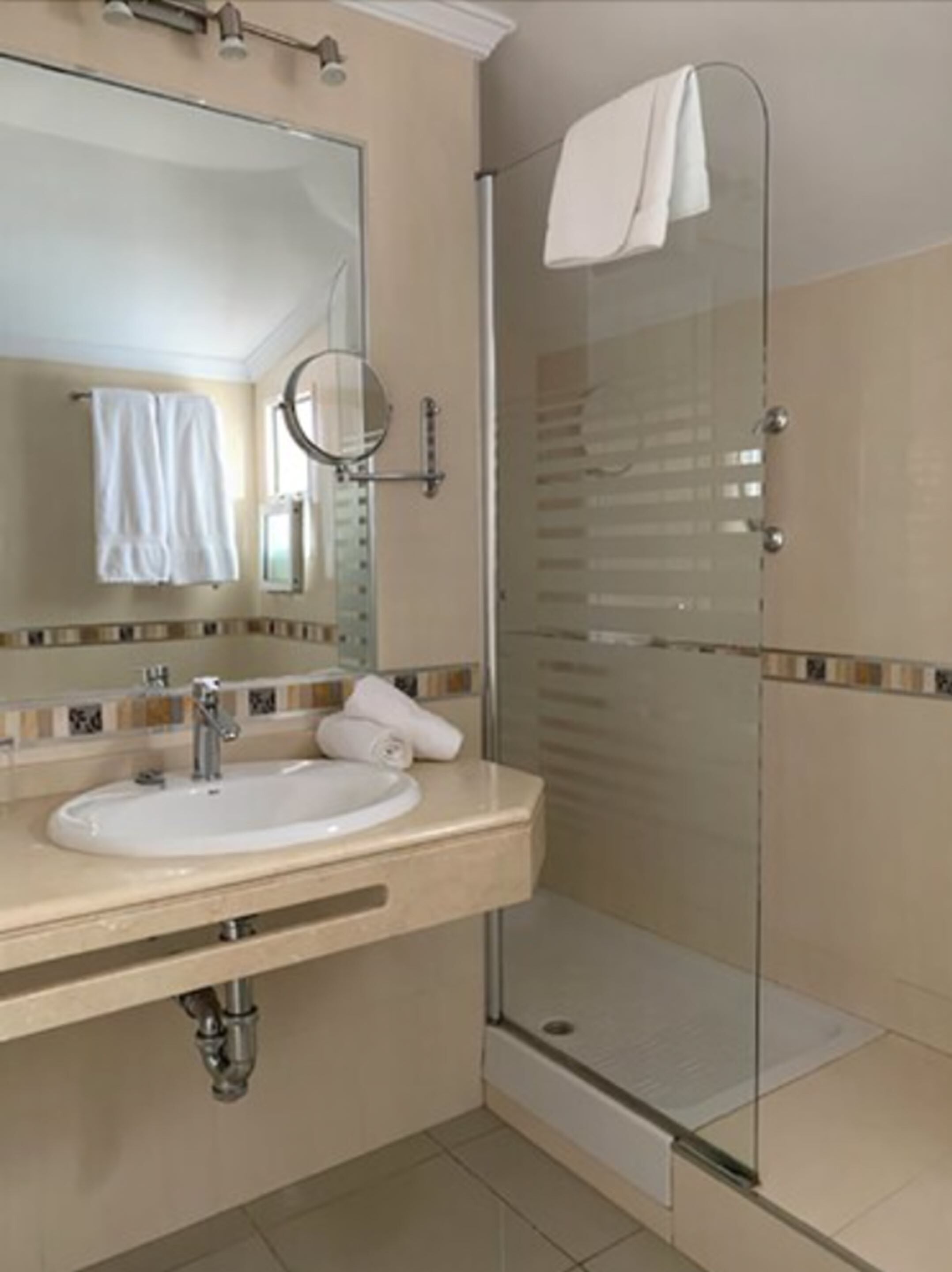 A modern bathroom with a sink, mirror, and glass shower enclosure.