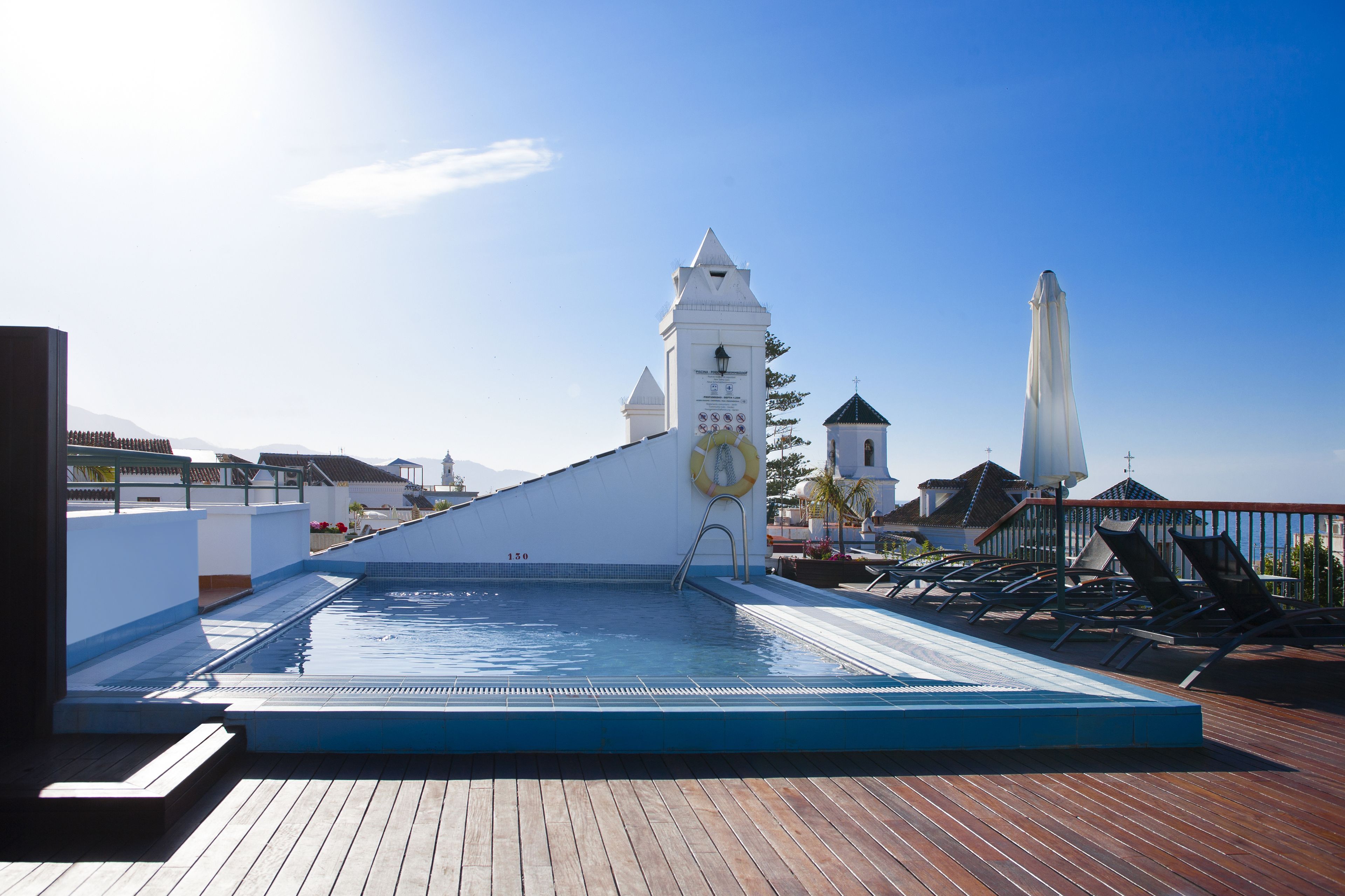 Une piscine sur le toit, agrémentée d’une tour horlogée, de chaises longues et d’une terrasse en bois.
