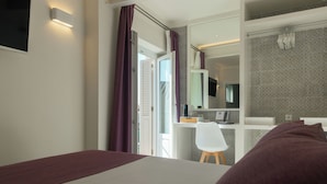 Una habitación de hotel moderna con cama, escritorio y silla. Hay un espejo en la pared y una ventana con cortinas moradas.