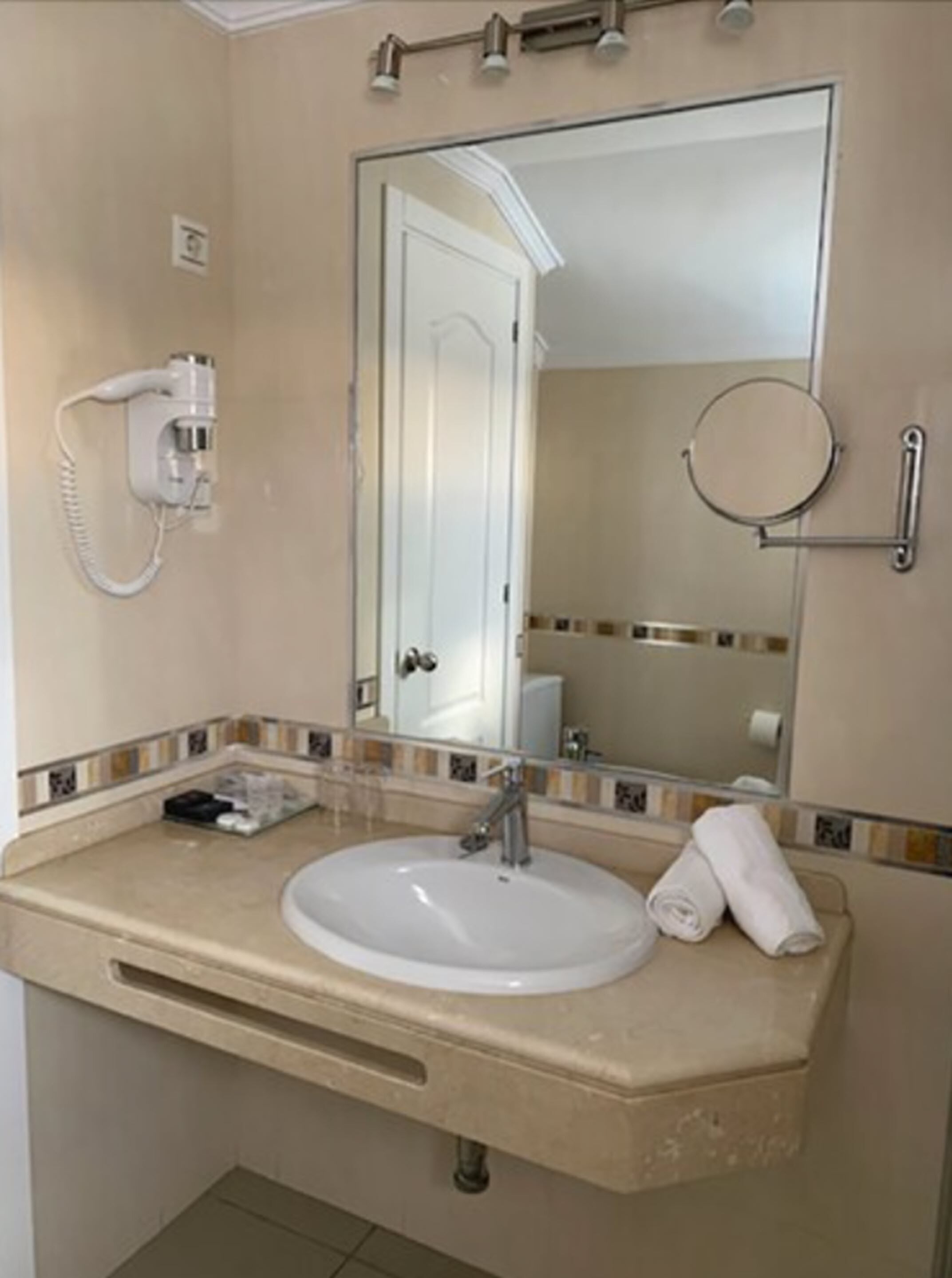 A bathroom with a sink, mirror, towel, and a hairdryer.