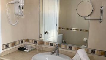 A bathroom with a sink, mirror, towel, and a hairdryer.