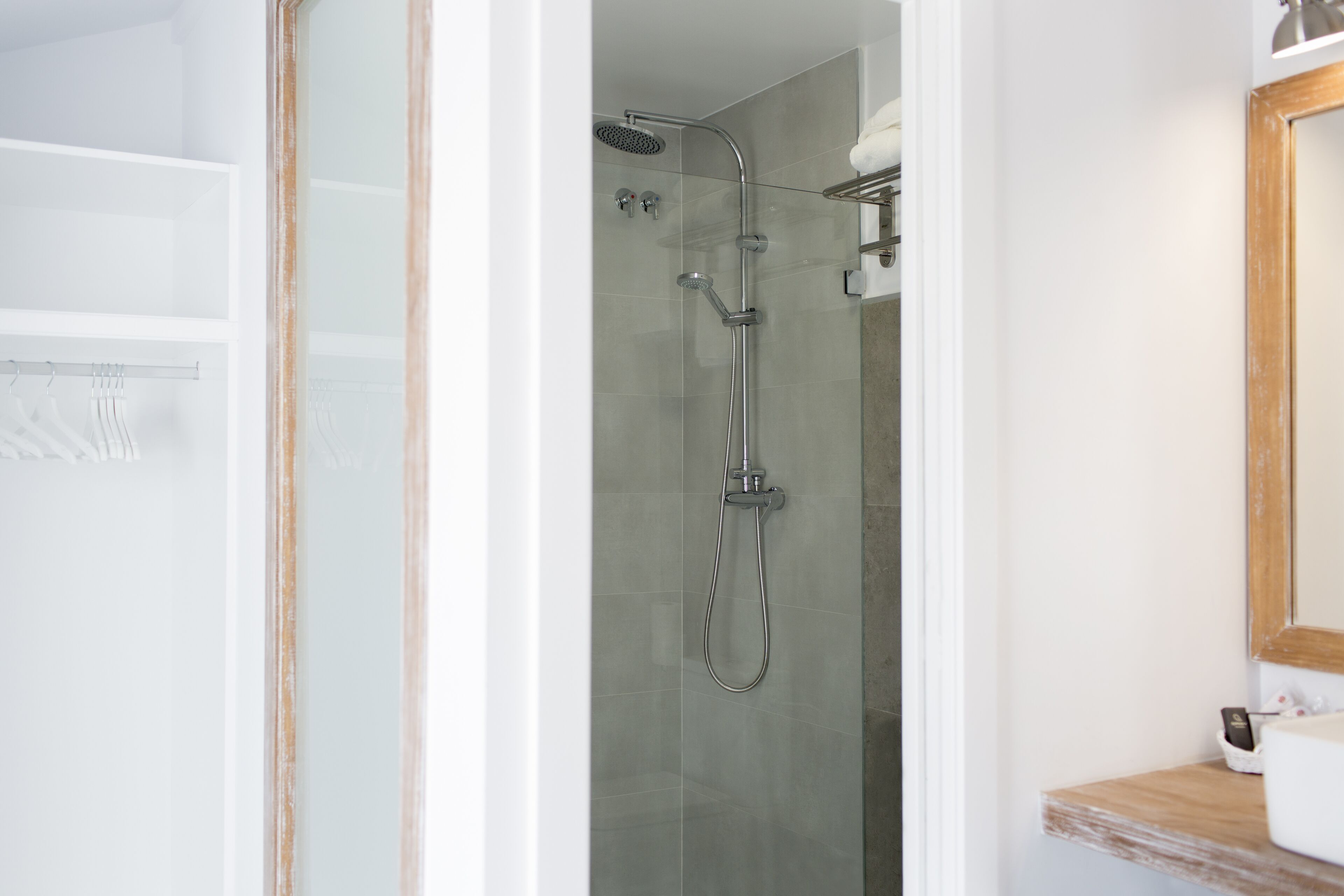 A modern bathroom with a glass-enclosed shower, a wooden vanity, and a mirror above the sink.