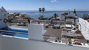 Zona de piscina con sillones y vista al mar.