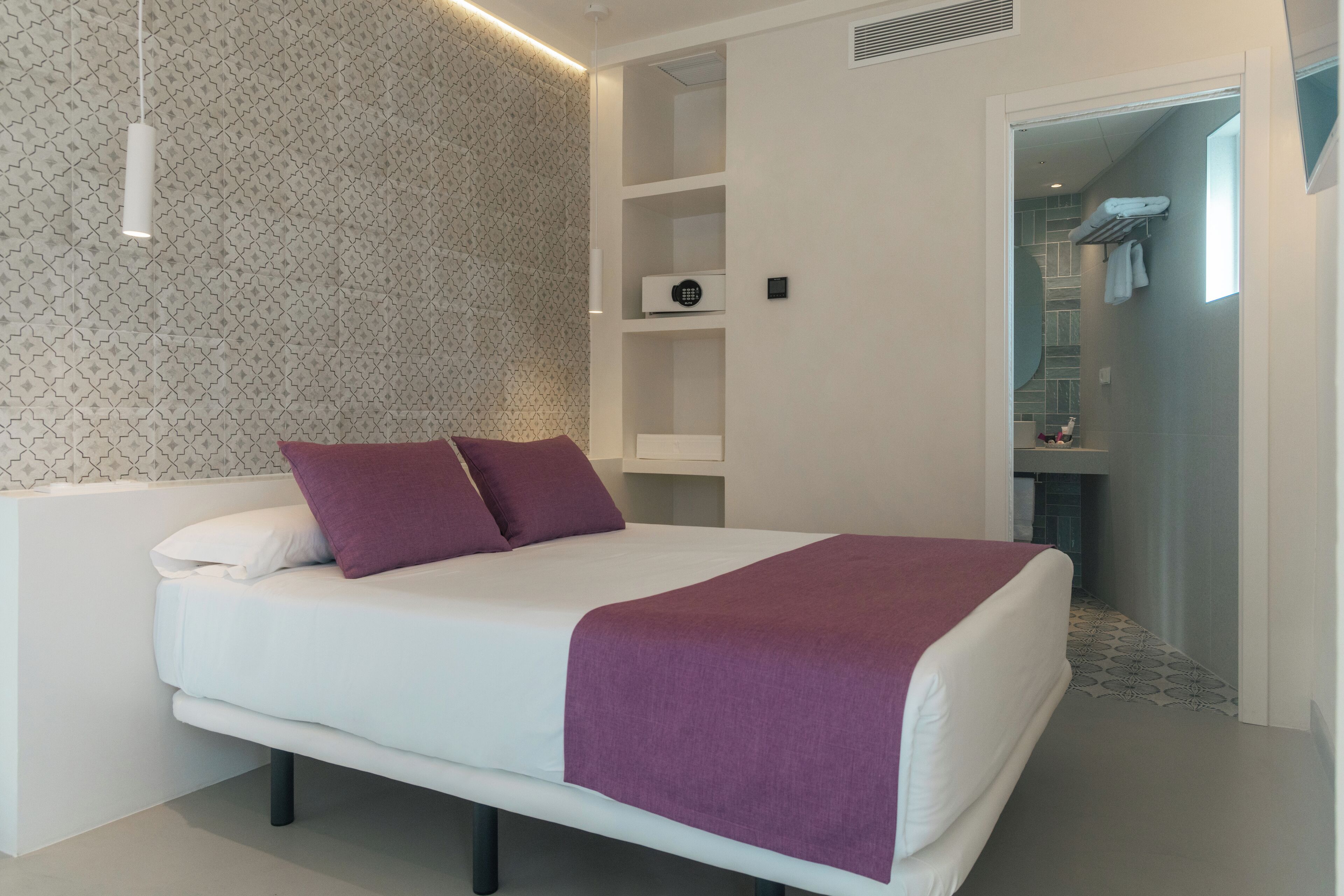Een moderne slaapkamer met een groot bed, inbouwkasten en een inloopkast.