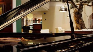 A grand piano in a hotel lobby with a decorative tree and a modern chandelier. - Sansi Barcelona (Barcelona)