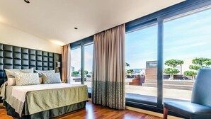 A modern hotel room with a large bed, a seating area, and a view of the cityscape. - Sansi Barcelona (Barcelona)