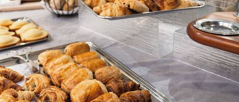 A buffet table with various pastries and a coffee dispenser.
