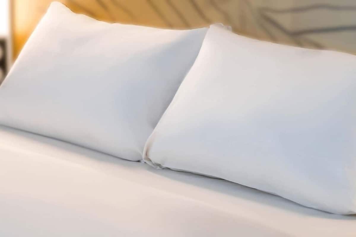 Un gros plan d’un lit avec une literie et des oreillers blancs.