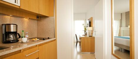 A compact kitchen with wooden cabinets, a coffee maker, and a countertop.