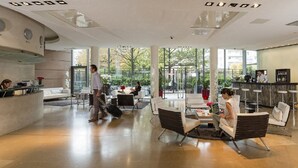 A spacious lobby with a reception desk, seating area, and a view of the outdoors. - Residhome Courbevoie La Défense (Courbevoie)