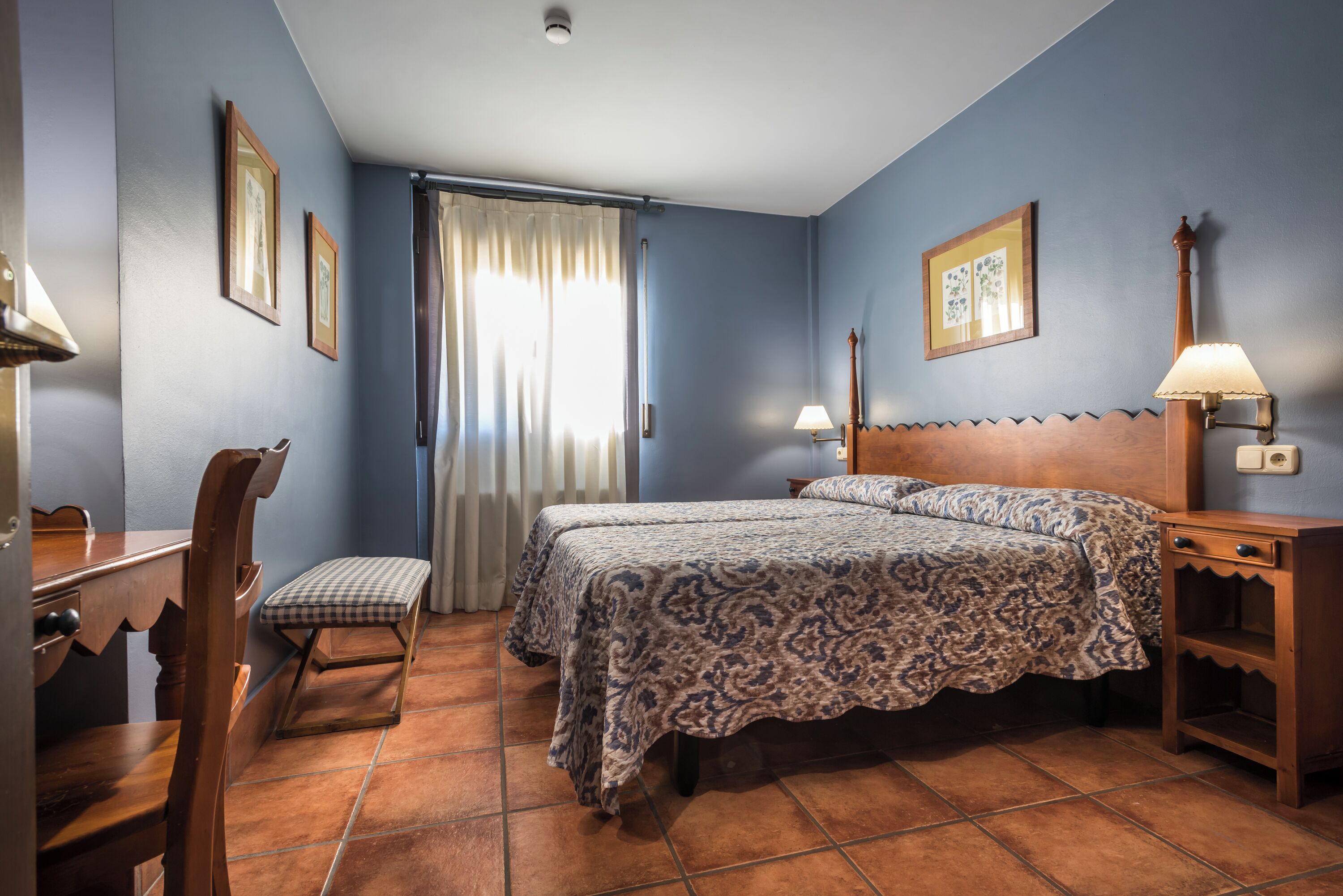 Un dormitorio con dos camas, un escritorio, una silla y una mesita de noche.