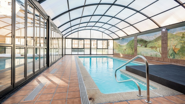 An indoor swimming pool with clear glass walls, a tiled floor, and a mural on the wall. - El Refugio de Aran Vielha Aparthotel (Vielha e Mijaran)