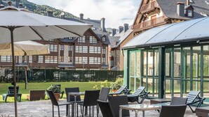 An outdoor patio with stone flooring, tables, chairs, and umbrellas. - El Refugio de Aran Vielha Aparthotel (Vielha e Mijaran)