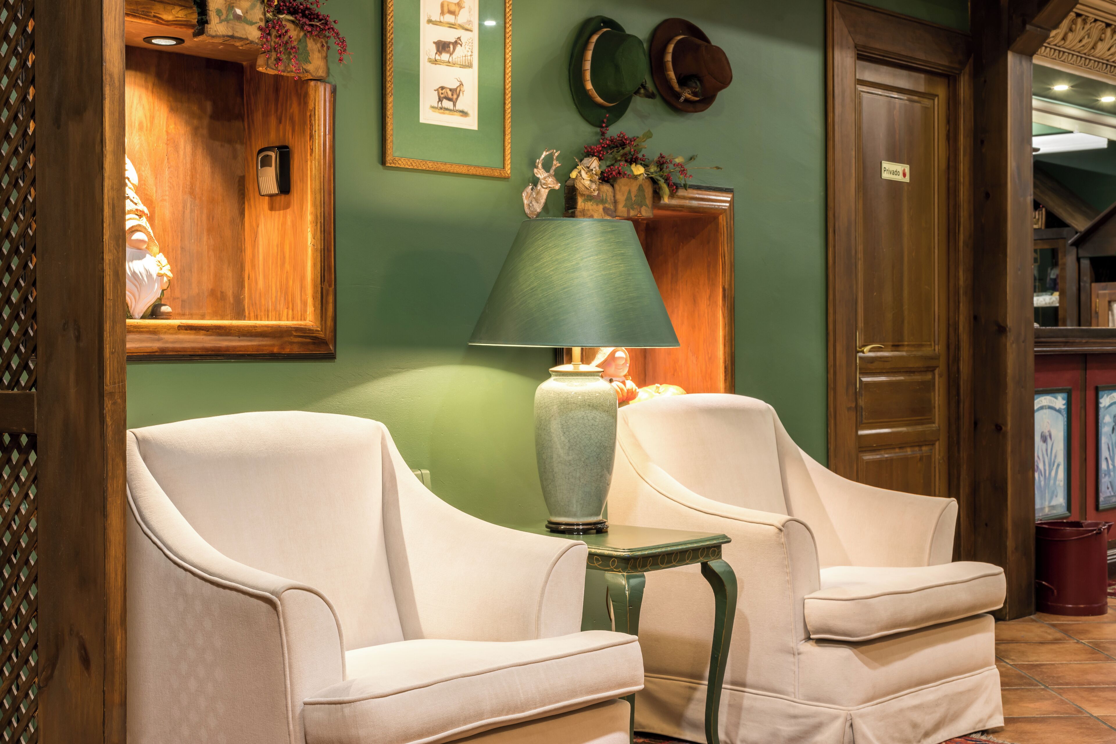 Una habitación con dos sillones blancos, una mesa verde, una lámpara verde y una puerta de madera.