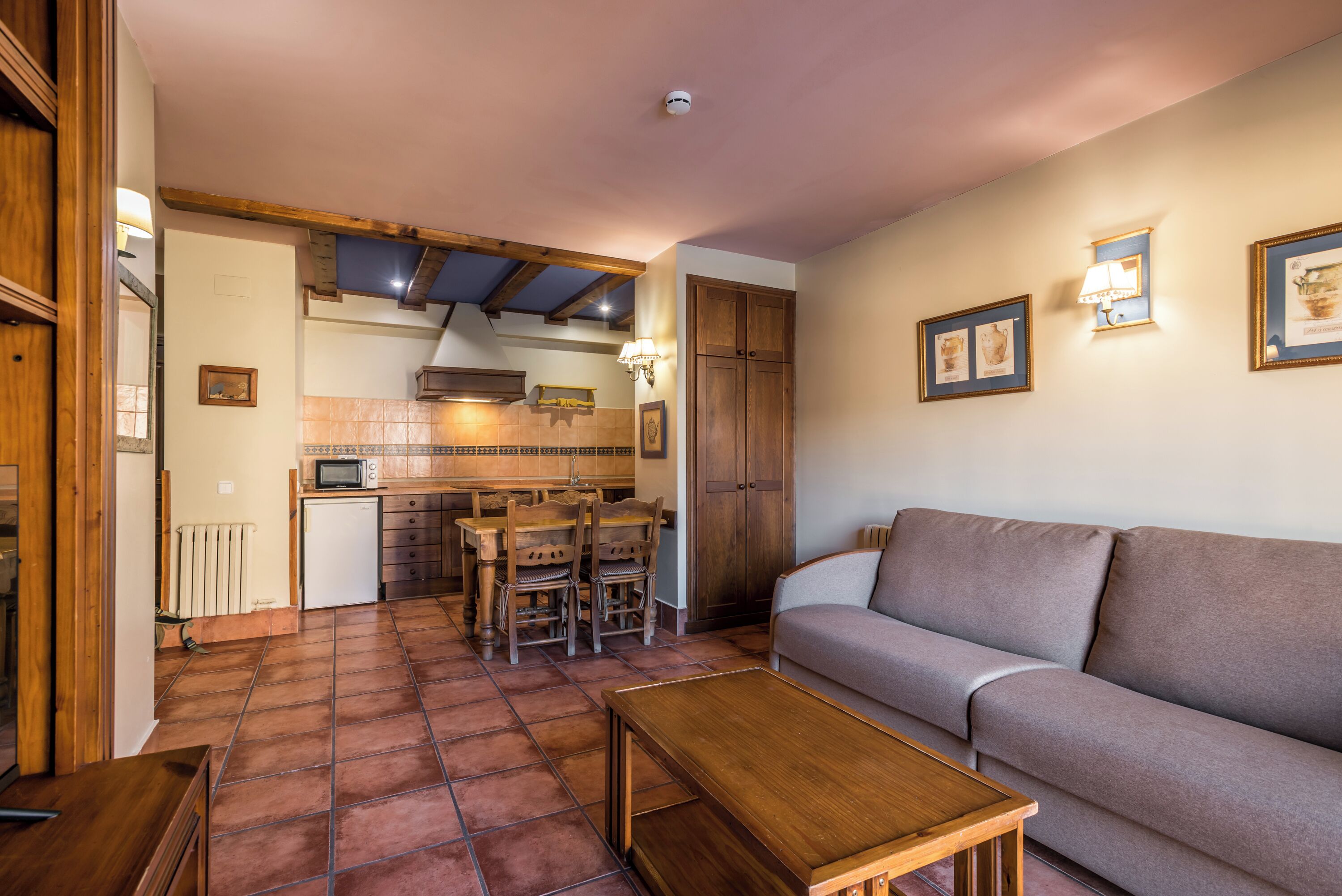 A cozy living room with a sofa, a wooden coffee table, and a kitchen area with a dining table and chairs.