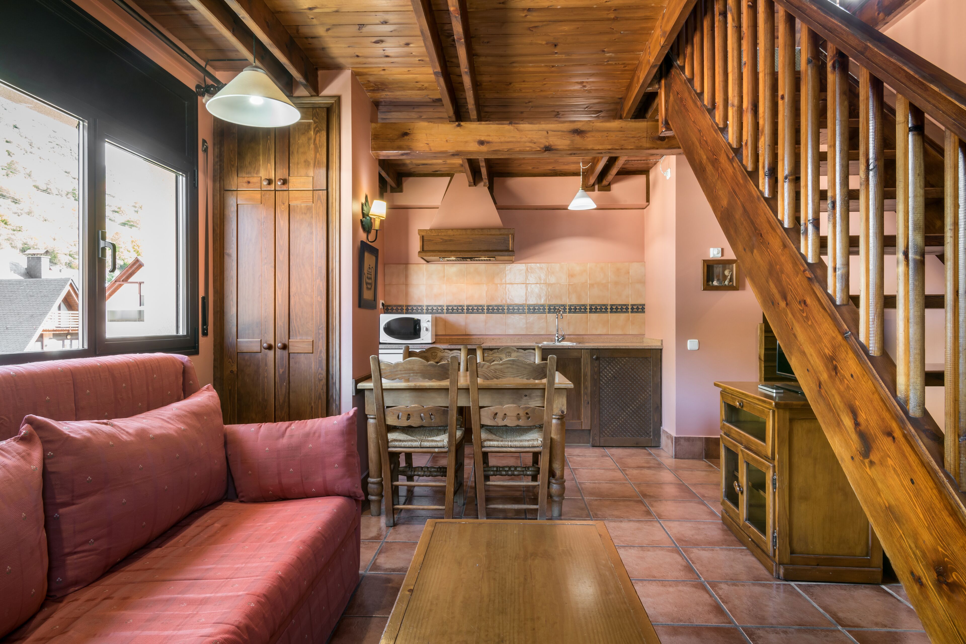 A cozy living area with a wooden staircase, a sofa, and a dining table.