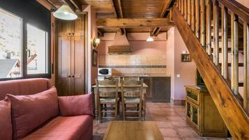 A cozy living area with a wooden staircase, a sofa, and a dining table.