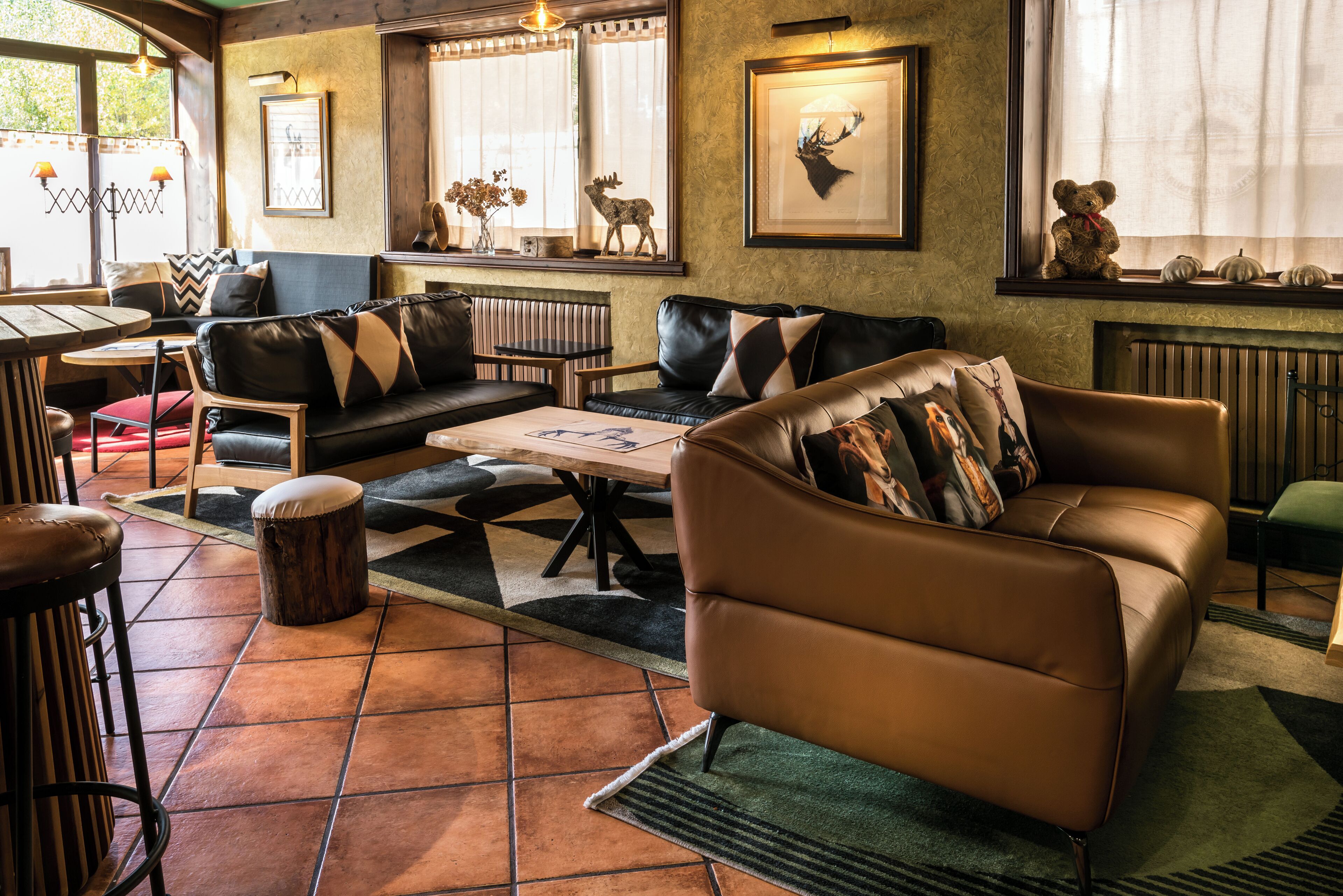 Uma sala de estar aconchegante com sofás de couro, uma mesa de centro e uma lareira. Há objetos decorativos na manta e uma janela com cortinas.
