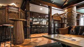 A bar area with stools, a wooden table, and a stone pillar. - El Refugio de Aran Vielha Aparthotel (Vielha e Mijaran)