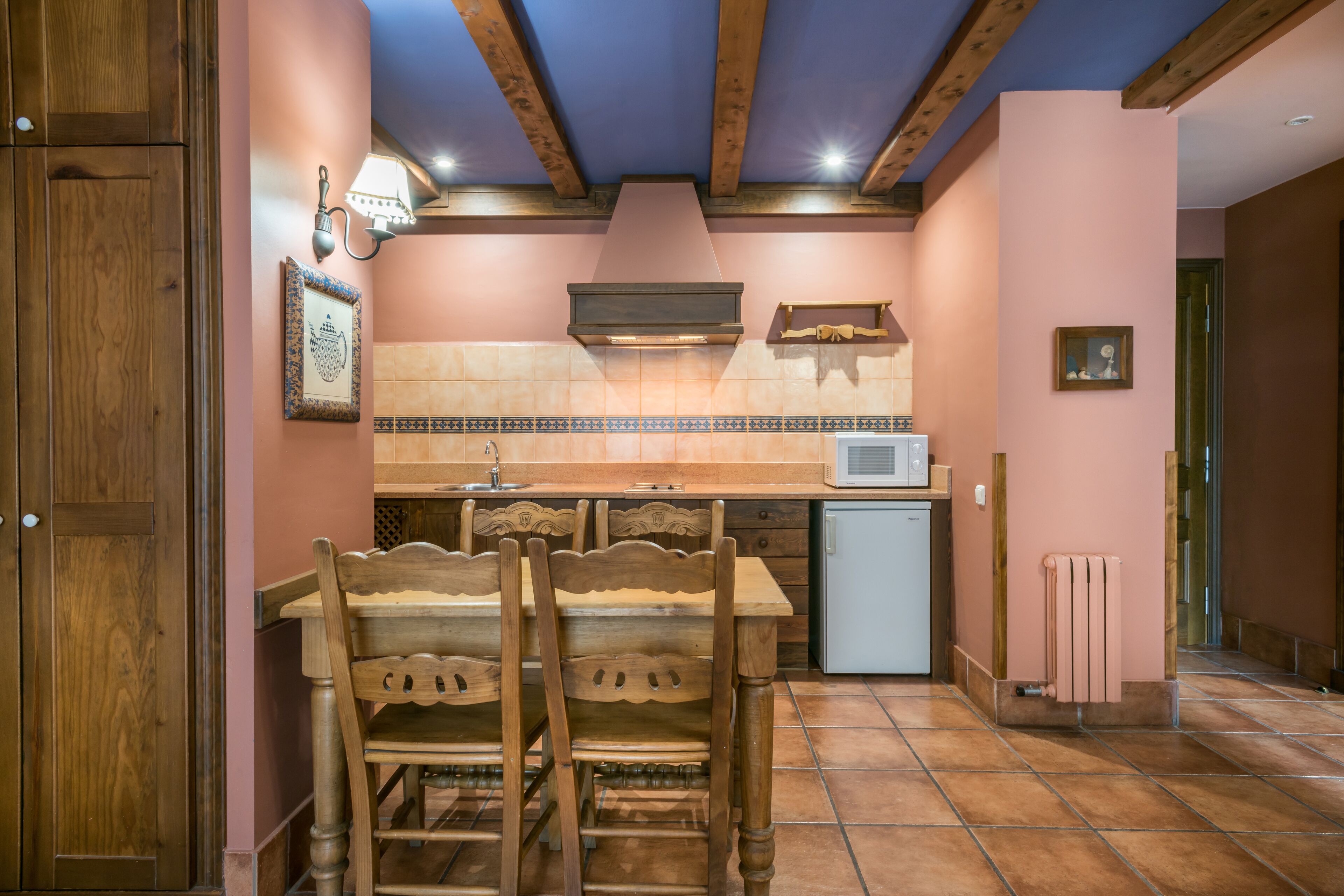 Una cocina con armarios de madera, salpicadero de azulejos y microondas integrado.