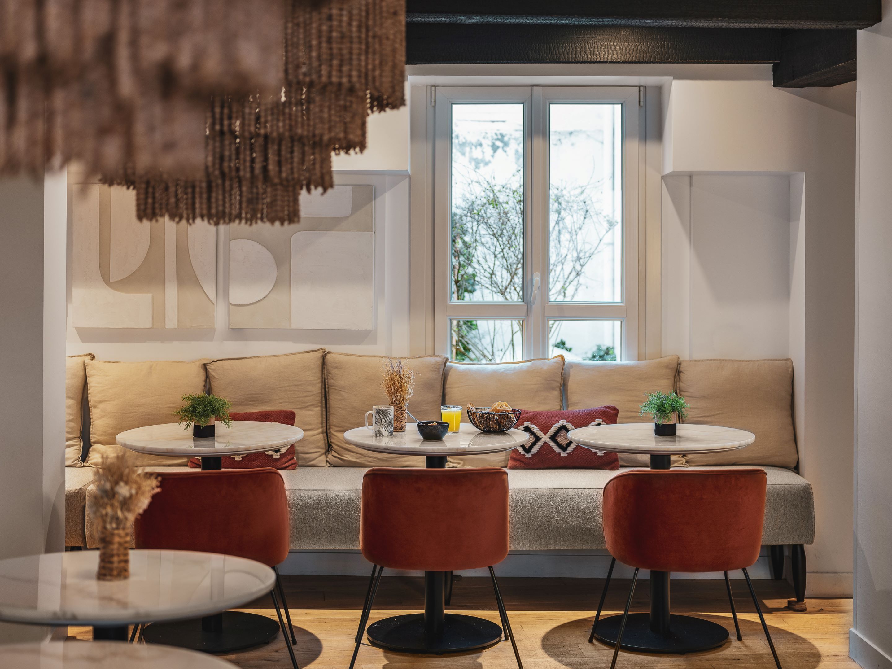 Een moderne woonkamer met een bank, twee ronde tafels en rode stoelen.