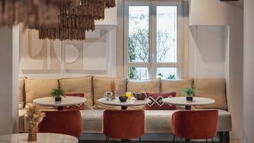 A modern living room with a sofa, two round tables, and red chairs.