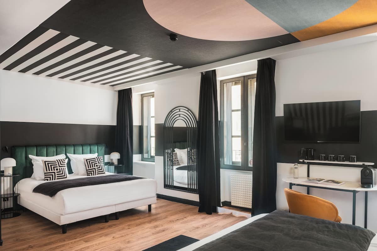 Una habitación de hotel moderna con una cama grande, un escritorio, un televisor de pantalla plana y vistas a la ciudad.
