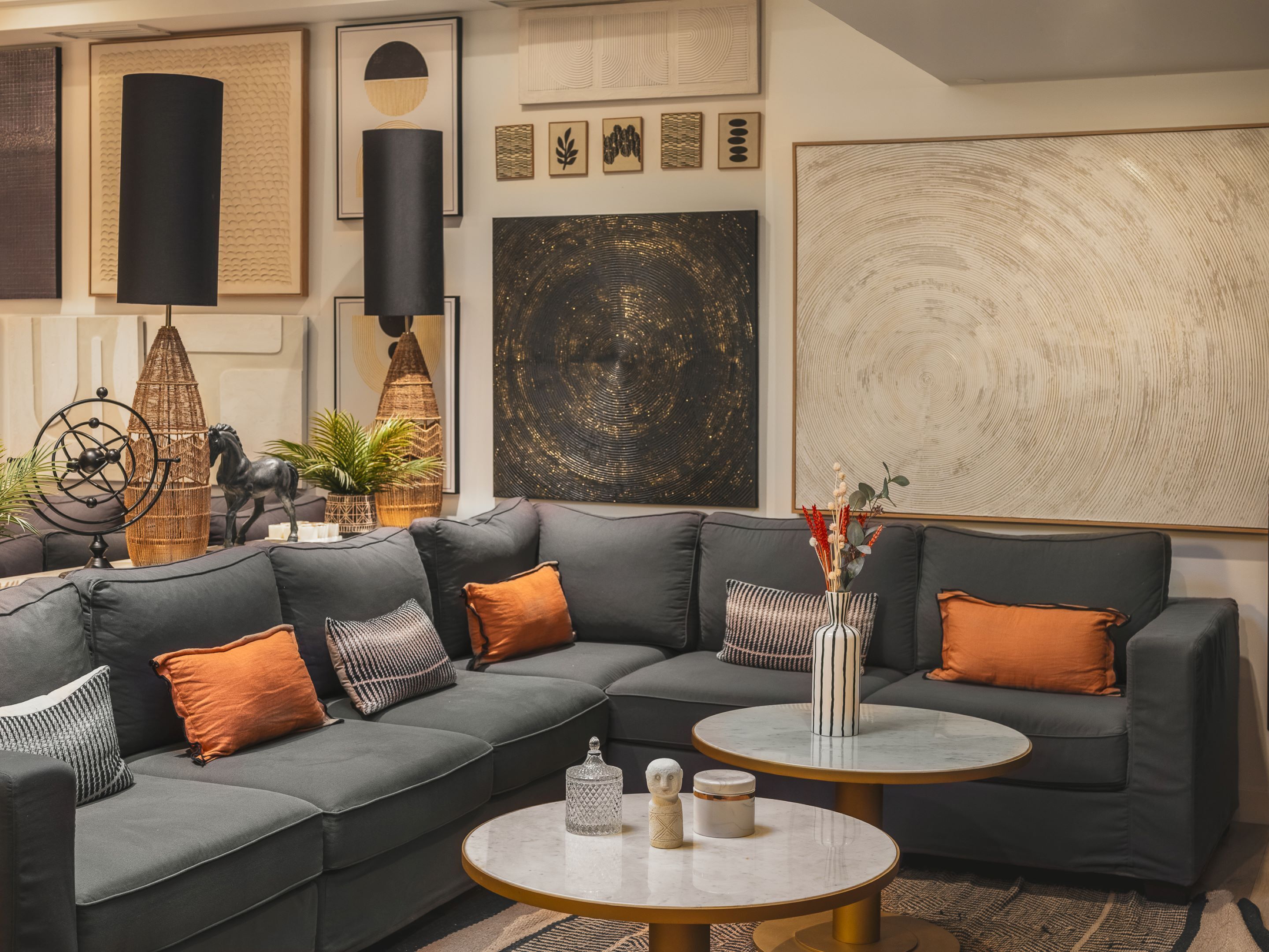 A modern living room with a sectional sofa, two round coffee tables, and various decorative items including wall art and a sculpture.