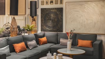 Un salon moderne avec un canapé d’angle, deux tables basses rondes et divers objets décoratifs, notamment des œuvres d’art mural et une sculpture.